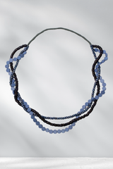 Necklace with blue and black beads on a gray background