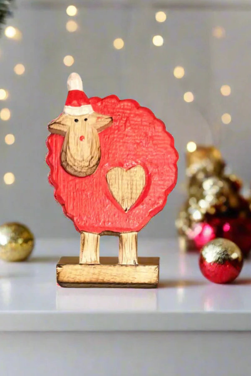 Decorative sheep figurine with a red coat and Santa hat on a white surface with Christmas decorations.