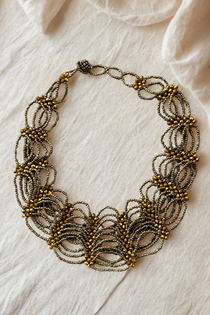 Decorative necklace with gold and bronze elements on a light fabric background
